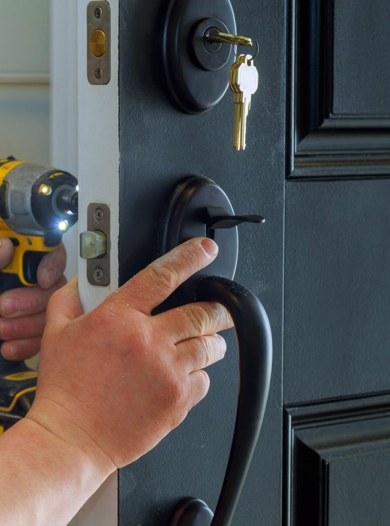 Closeup of a professional locksmith installing a new lock on a house exterior door with the inside